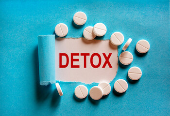 The word 'detox' appearing behind torn blue paper. White pills. Beautiful blue and white background.