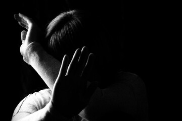 Black and white portrait of a woman hiding her face with hands. Stop violence against woman or...