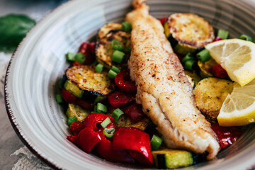 Plat de poisson filet de colin accompagné de légumes courgettes poivrons citron frais