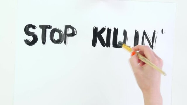 timelapse. close-up, hand writes slogan - Stop killing Black People - with brush, using black paint on white poster. Fighting against racism, for equal rights in USA.
