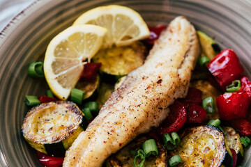 Plat de poisson filet de colin accompagné de légumes courgettes poivrons citron frais