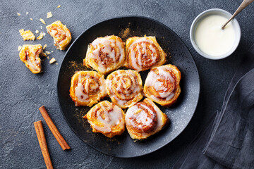 Cinnamon rolls on black plate. Grey background. Close up. Top view.