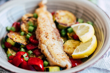 Plat de poisson filet de colin accompagné de légumes courgettes poivrons citron frais