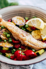 Plat de poisson filet de colin accompagné de légumes courgettes poivrons citron frais