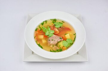 soup with meat, pepper, tomatoes, greens on a white background