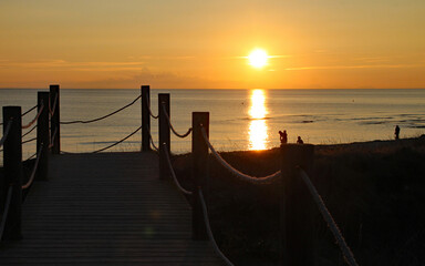 People in the sea enjoy the last of the evening sun before setting off home on the wooden boardwalk...