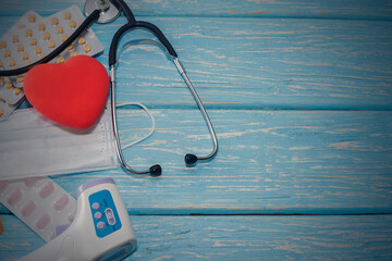 A heart with a stethoscope lies on a wooden background. Healthy heart