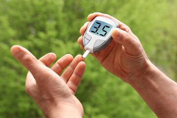 male hands closeup, a man does a nature test with a glucometer, medical concept, blood glucose control, diabetes