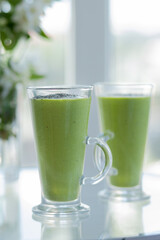 for breakfast two green cocktail detox smoothies on the glass table. Side view