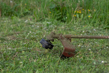 Obraz premium A lawnmower on the grass close-up. A garden tool.