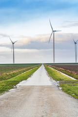 Fototapeta na wymiar Small road between wind electricity heading to coast of north Netherlands near Eemshaven in winter
