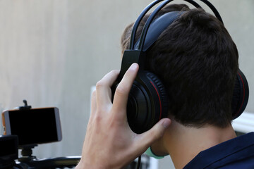 Closeup photography of a videographer working outdoor,holding his headphones and microphone.Face mask as protection from covid on the face.