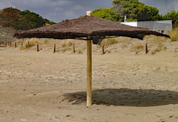 Fototapeta na wymiar Straw sun umbrella on a sandy beach