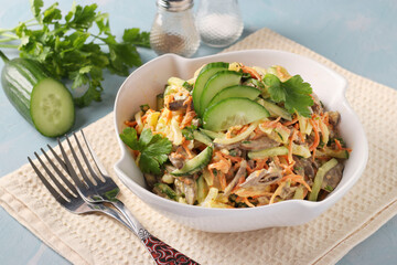 Salad with chicken hearts, cucumber, carrots and onions in white bowl on light blue background, Horizontal format © Anzhela