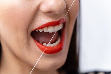 Woman flossing his teeth with dental floss. Close-up, cropped photo.