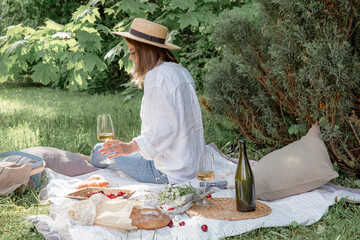 Woman in straw hat on picnic holding a glass of wine from behind. Summer time adventures