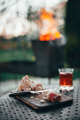 Meat being cut on parts and prepared for barbecue, with glass of whiskey and fire at the background. 