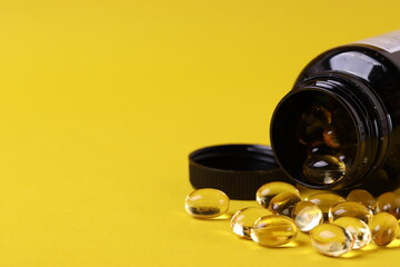  fish oil omega three capsules on the yellow background as a healthy balanced diet concept or...