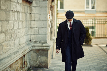 Portrait of retro 1920s english arabian business man wearing dark coat, suit, tie and flat cap.