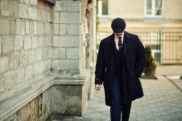 Portrait of retro 1920s english arabian business man wearing dark coat, suit, tie and flat cap.