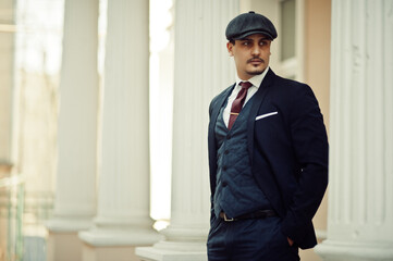 Portrait of retro 1920s english arabian business man wearing dark suit, tie and flat cap.