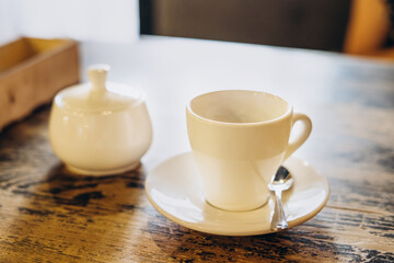 Fototapeta na wymiar Aromatic fresh coffee in a white cup. Americano with sugar bowl on table in cafe. Americano in a small white cup.