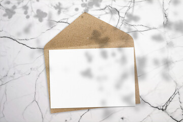 Blank greeting card and craft paper envelope on marble background