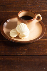 Small round cookies and Cup of coffee in brown dish on wooden table.