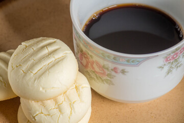 Small round cookies and Cup of coffee in brown dish on wooden table.