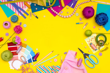 DIY. Multicolored craft supplies and tool on yellow background. Womens hobby - sewing, embroidery, felt craft, scrapbooking. Copy space.