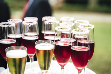 Several glasses with various colorful beverages. Alcoholic drinks in dewy glasses. Outdoor background. Celebration, birthday, party, wedding concept.
