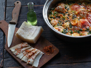 Homemade delicious food, fried eggs, chopped bacon with paprika and a bottle of grappa.