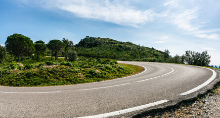 Empty long mountain road to the horizon on a sunny summer day at bright sunset