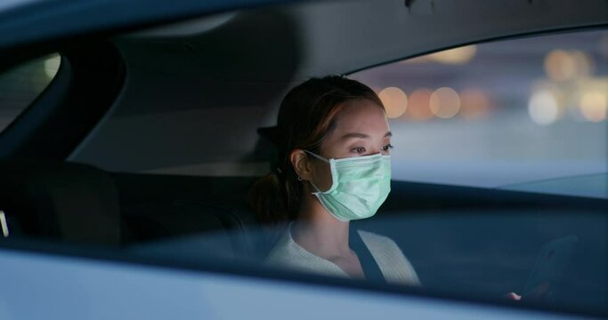 Woman wear face mask and sit inside car at night