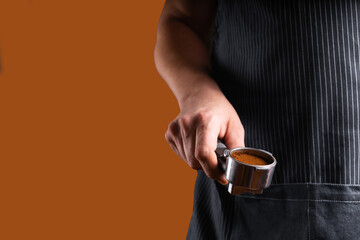 A man with a portafilter in his hands. The concept of making coffee in a coffee machine. Photo in a low key.