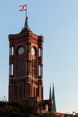 The tower of the Rotes Rathaus (English: Red City Hall), and the red and white flag with coat of arms of the city, fluttering in the wind at the top of a pole. Berlin's renowned red brick town hall