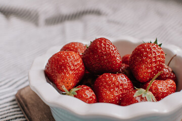 Strawberries in a plate on the wooden board. Summer concept.