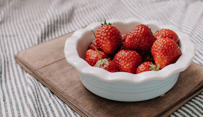 Strawberries in a plate on the wooden board. Summer concept.