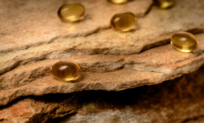 Vitamin capsules. Soft gel capsules on the surface of natural stone. Сlose up fish oil on gold background. Omega 3. Сoncept of health. Омега 3. gold pattern