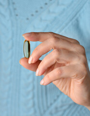 Woman hand holds yellow medication capsules of omega 3, pours from a white bottle into palm the fish oil, healthy supplement pills. Омега 3. Витамин Е