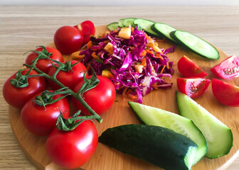 Salad and cherry tomatoes on a wooden board, view from above