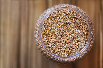 Wheat inside the bowl on a wooden table. View from above.