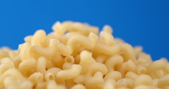 A handful of dry pasta of cavatappi rotates slowly.