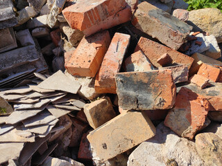 Old broken red bricks lie in a mess outdoors