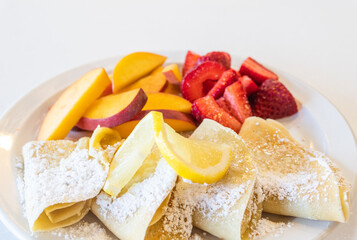 Crepes with Sliced Lemon, Peaches, Strawberries and Powdered Sugar
