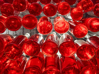 Bottles with beverage. Bottoms of the bottles with red drink. Many glass bottles of red drink. Wine business. Many glass bottles of red wine with a volume of 0.5 liters. Storage of bottled drinks
