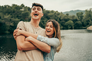 Boyfriend and girlfriend in love and smiling on a lake.