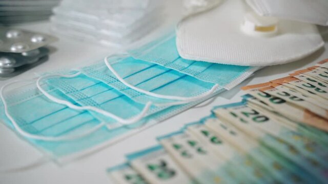 Increasing prices in medical industry and development of pharmaceutical business, high cost medicine. Pile of euro banknotes scattered on the table among medical masks and different pills, capsules