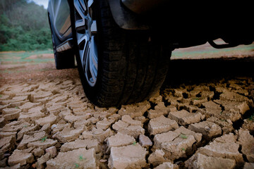 Close up vehicle wheel parking on dry soil crack represent global environment problem or Drought issue