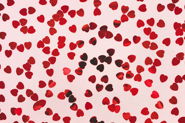 Romantic pink festive backround with red heart shaped confetti. Love, dating and Valentines Day concept